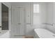 Bright bathroom featuring neutral tiling, double doors to closet, and a modern soaking tub at 18 Logan St, Charleston, SC 29401