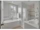 Bright bathroom features a modern tub, open shower, neutral tiling, and shuttered windows at 18 Logan St, Charleston, SC 29401