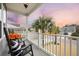 Charming front porch with rocking chairs and a view of the neighborhood street and mature palm trees at 213 Palmetto Walk Dr, Summerville, SC 29486