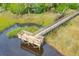 Aerial shot of a wooden boardwalk and viewing platform on the water amidst lush marsh grasses at 2176 Andover Way, Mount Pleasant, SC 29466