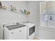 Clean laundry room includes modern washer, dryer and storage shelves, illuminated by natural light at 225 Bird Song Path, Summerville, SC 29485