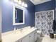 Well-lit blue bathroom with a white countertop vanity, modern faucet, and a shower with patterned curtain at 2419 Tuscany Dr, North Charleston, SC 29406