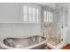 Bright bathroom with soaking tub, wooden floors, shutters, and glass shower at 25 Logan St, Charleston, SC 29401