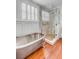 Bright bathroom with soaking tub, wooden floors, shutters, and glass shower at 25 Logan St, Charleston, SC 29401