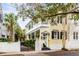 Charming yellow house with a white porch, black shutters, landscaping, and palm trees at 25 Logan St, Charleston, SC 29401