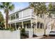 Beautiful two-story home with a yellow exterior, a white porch, black shutters, and landscaping at 25 Logan St, Charleston, SC 29401