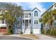 Charming two-story beach home featuring a double front porch, light blue siding, and dual garage doors at 27 Ocean Point Dr, Isle of Palms, SC 29451