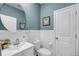Stylish powder room features blue wallpaper, white wainscoting, and a modern round mirror at 3213 Great Egret Dr, Johns Island, SC 29455