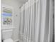 Bright bathroom with window shutters, a white toilet, and a gray and white patterned shower curtain at 3213 Great Egret Dr, Johns Island, SC 29455