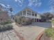 Rear exterior view of the home with an inviting covered porch, brick accents, and a spacious driveway at 547 Island Walk, Mount Pleasant, SC 29464