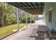 Covered patio space with wooden picnic table and views of the lush green lawn and nearby street at 6 4Th Ave, Isle of Palms, SC 29451