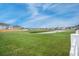 Spacious backyard with a pond beyond the green grass area surrounded by white fence in a home community at 641 Sienna Way, Summerville, SC 29486