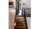 Wood stairs with a black metal railing lead to an open hallway with a door and window in a naturally lit home at 71 Wentworth St # 302, Charleston, SC 29401