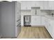 Bright kitchen with stainless steel appliances, white cabinetry, modern backsplash, and hardwood style floors at 7629 Vanderbrook Pl, North Charleston, SC 29420
