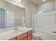 Well-lit bathroom featuring a double vanity, framed mirror, and shower with glass doors at 8475 Athens Way, North Charleston, SC 29420
