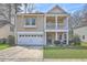 Charming two-story home boasts a welcoming porch, a well-manicured lawn, and an attached two-car garage at 8475 Athens Way, North Charleston, SC 29420