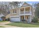 Inviting two-story home featuring a cozy front porch, lush green lawn, and an attached two-car garage at 8475 Athens Way, North Charleston, SC 29420