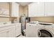 Spacious laundry room with overhead cabinets, sink, and front loading washer and dryer at 93 Surfscoter Ln, Kiawah Island, SC 29455