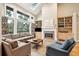Bright living room with fireplace, hardwood floors, built-in shelving and large windows with backyard views at 93 Surfscoter Ln, Kiawah Island, SC 29455