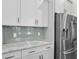 Modern kitchen features white cabinets, stainless steel refrigerator, tile backsplash, and granite countertops at 108 Whaler Ave, Summerville, SC 29486