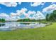 Picturesque pond surrounded by verdant green grass and mature trees under a beautiful blue sky with fluffy white clouds at 108 Whaler Ave, Summerville, SC 29486