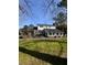 Expansive backyard view with a brick chimney, sunroom, green lawn and mature trees under a blue sky at 122 Mellard Dr, Goose Creek, SC 29445