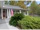Close-up view of a cozy front porch featuring an American flag, a dark front door, and vibrant greenery at 132 Lipman St, Summerville, SC 29483