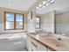 Bathroom featuring double sinks, a large mirror with Hollywood lights, and a large tub by the window at 1615 E Ashley Ave, Folly Beach, SC 29439