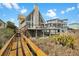 Beach house with wooden walkway and a large deck, offers seamless transition from home to beachside serenity at 1615 E Ashley Ave, Folly Beach, SC 29439