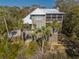 Coastal home featuring a metal roof and wrap around porch, surrounded by lush greenery and palms at 308 Jungle Rd, Edisto Beach, SC 29438