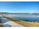 Scenic lake view with a walking path and neighborhood homes in the background, perfect for serene living at 3278 Great Egret Dr, Johns Island, SC 29455