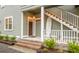 Charming covered front porch with steps, plants and a white surfboard adding coastal flair at 493 Woodland Shores Rd, Charleston, SC 29412