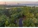Aerial view of land with a gravel road flanked by verdant trees, bordering marshland at 509 Seven Farms Dr, Charleston, SC 29492