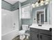 A blue bathroom features a shower-tub combo, a window, and a sink with a black cabinet at 110 Instructor Ct, Ladson, SC 29456