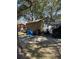 A detached garage with a metal door with yard tools and tarps around the garage and a small red house in the background at 111 Newington Rd, Summerville, SC 29485