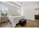 Bright bedroom with hardwood floors, tray ceiling, ceiling fan, shutters, and an upholstered ottoman at the foot of the bed at 2014 Barn Swallow Rd, Summerville, SC 29483