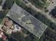 Aerial view of a .61 acre residential lot surrounded by mature trees, a nearby home and pool at 207 S Gum St, Summerville, SC 29483