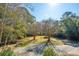 Expansive backyard featuring mature trees and a gravel driveway at 207 S Gum St, Summerville, SC 29483