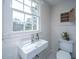 Bright bathroom featuring a sink, toilet, white walls, decorative tiling, and a window providing natural light at 207 S Gum St, Summerville, SC 29483