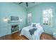 Light-filled bedroom with wood floors, fireplace, ceiling fan, and neutral decor at 207 S Gum St, Summerville, SC 29483