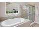 Bright bathroom featuring a soaking tub and a glass-enclosed shower, complemented by a large window at 2124 Tall Grass Cir, Mount Pleasant, SC 29466