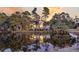 Exterior view of the house with lights on reflecting in the pond surrounded by luscious green trees at sunset at 31 Berkshire Hall, Kiawah Island, SC 29455