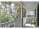 Covered porch featuring bright green chairs, white railings, and views of the surrounding trees at 31 Berkshire Hall, Kiawah Island, SC 29455