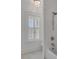 Bright bathroom featuring a window with shuttered blinds, white tile, and a bathtub with chrome shower fixtures at 3699 Goodwater St, Mount Pleasant, SC 29466