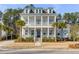 Stunning two-story white home boasts a charming double porch and lovely front yard with mature palm trees at 3699 Goodwater St, Mount Pleasant, SC 29466