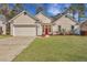 Charming home featuring a well-manicured lawn, attached garage, and bright red front door at 5420 Percival Ln, North Charleston, SC 29420