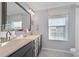 Bathroom vanity features dual sinks, grey cabinets, and a window with a sheer, lacy curtain at 625 Sienna Way, Summerville, SC 29486