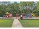 Community playground with swings, slides, and other colorful equipment, surrounded by green grass and tall trees at 659 Hamlet Cir, Goose Creek, SC 29445