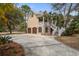 Charming tan home with wooden garage doors, brick accents and a inviting staircase to a quaint front porch at 7759 Edingsville Beach Rd, Edisto Island, SC 29438