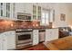 Modern kitchen featuring stainless steel appliances, white cabinets, and brick backsplash at 7759 Edingsville Beach Rd, Edisto Island, SC 29438